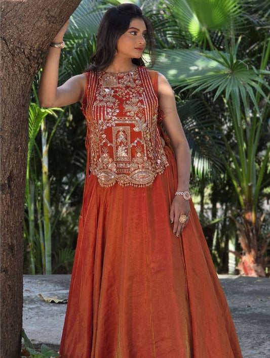 rust orange sleeveless lehenga with heavy gold embroidery and a flared silk skirt.