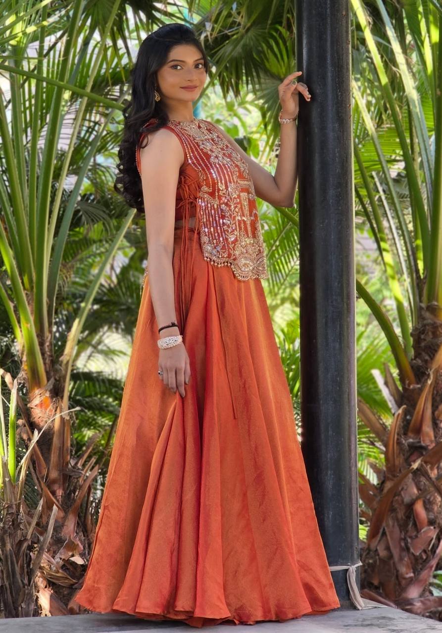 rust orange sleeveless lehenga with heavy gold embroidery and a flared silk skirt.